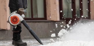 Man cleans street from snow with blower